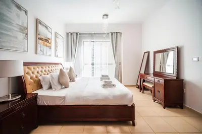 a bedroom with a bed and a desk and a mirror at Top Holiday Location - Walk to Beach - Free Pool & Gym in Dubai