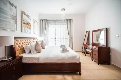 a bedroom with a bed and a desk and a mirror at Top Holiday Location - Walk to Beach - Free Pool & Gym in Dubai