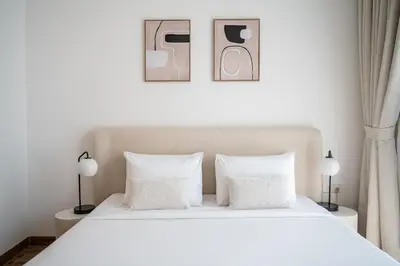 a bedroom with a large white bed with two lamps at Brand New 2BR -Spacious in Dubai