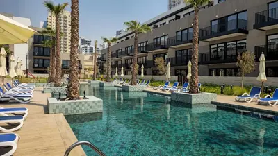a pool with chairs and palm trees in a building at Brand New 2BR -Spacious in Dubai