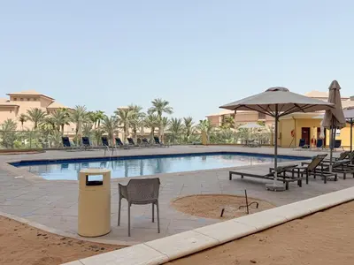 a pool with chairs and an umbrella and a trash can at The Smart Concierge - Murjan in Dubai