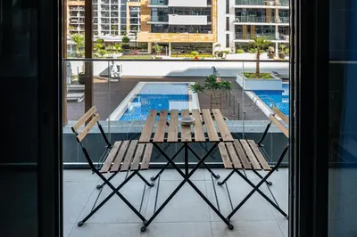 a table and chairs on a balcony with a pool at Upscale 1 Bedroom Apartment - Azizi Riviera 27 - Allsopp & Allsopp in Dubai