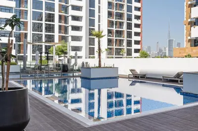 a pool with a palm tree on the roof of a building at Upscale 1 Bedroom Apartment - Azizi Riviera 27 - Allsopp & Allsopp in Dubai