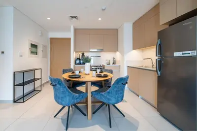 a kitchen with a wooden table and blue chairs at Elegant 1 Bed Creek Beach Stay with Beach Access in Dubai