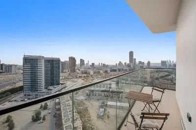 a balcony with two chairs and a view of a city at Cozy 1BR Apartment with Pool & Parking JVC Dubai in Dubai