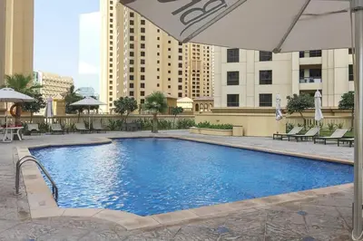 a large swimming pool with an umbrella and some buildings at Frank Porter - Rimal 1, JBR in Dubai
