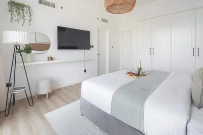 a white bedroom with a large bed and a tv at Frank Porter - Lago Vista Tower A in Dubai