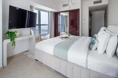 a white bedroom with a large bed with a flat screen tv at Frank Porter - Elite Residence, Dubai Marina in Dubai