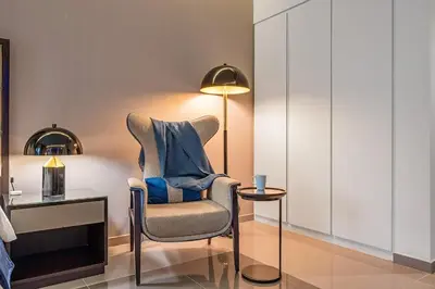 a room with a chair and a table and a lamp at DAMAC Majestine Studio with Pool, Spa and Gym Near Bus & DubaiMall in Dubai