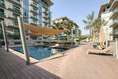 a swimming pool with a umbrella and chairs next to a building at Modern and Elegant 1 Bed Retreat in Prime Location in Dubai