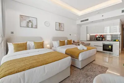 two beds in a white room with a kitchen at Nice New Studio 2 Double Beds In Downtown, Free Parking in Dubai