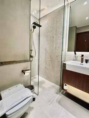 a bathroom with a shower and a toilet and a sink at Soft Toned 1BR Retreat with Pool, Gym and Parking! in Dubai