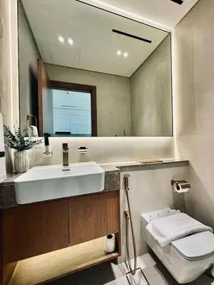 a bathroom with a sink and a toilet and a mirror at Soft Toned 1BR Retreat with Pool, Gym and Parking! in Dubai