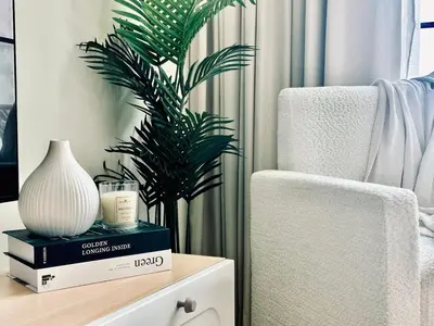 a plant sitting on top of a table next to a chair at Soft Toned 1BR Retreat with Pool, Gym and Parking! in Dubai