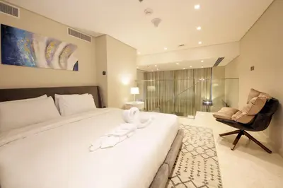 a bedroom with a large white bed and a chair at The Sterling By OMNIYAT Near To Dubai Mall in Dubai