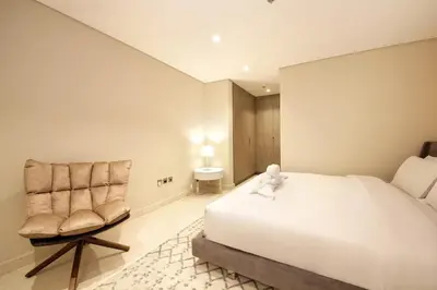 a bedroom with a white bed and a chair at The Sterling By OMNIYAT Near To Dubai Mall in Dubai