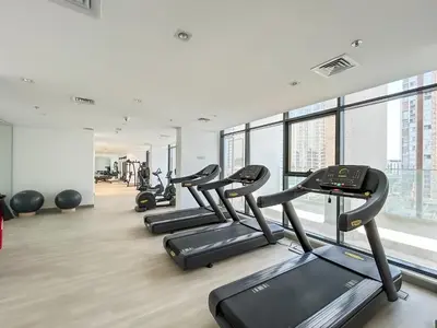 a gym with rows of treadms and cardio machines at Urban Family Home minutes from Downtown in Dubai