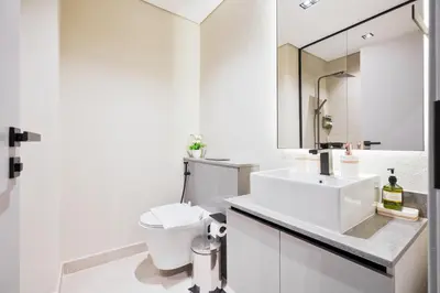 a white bathroom with a toilet and a sink at Posh Studio in MBR by Deleguest in Dubai