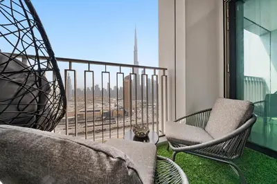 a balcony with two chairs and a cat sitting on the grass at Burj View Chic 2BR Downtown Dubai in Dubai