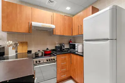 a kitchen with wooden cabinets and a white refrigerator at Stylish 1BR - Pool, Gym Access & City Skyline Views near JBR Beach in Dubai