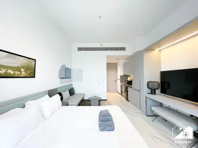 a white bedroom with a large bed and a tv at Luxury Studio in MAG City l Private Balcony in Dubai