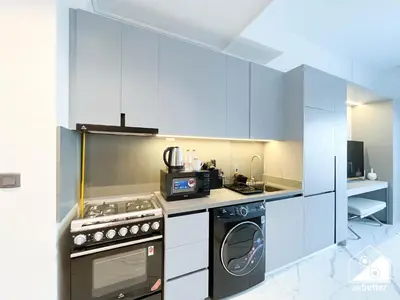 a kitchen with white cabinets and a stove and a microwave at Luxury Studio in MAG City l Private Balcony in Dubai