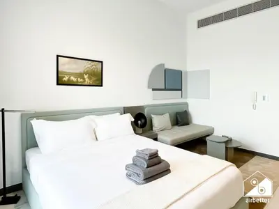 a bedroom with a white bed and a chair at Luxury Studio in MAG City l Private Balcony in Dubai