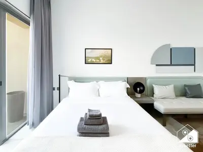 a bedroom with a white bed and a couch at Stylish Studio Living l MAG Meydan in Dubai