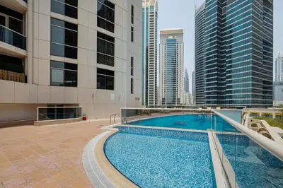 a swimming pool on the roof of a building with tall buildings at Luxury JLT Studio Renovated Lake View Metro in Dubai