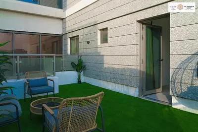 a patio with chairs and a table and grass at Serenity 1 bdr with private garden in Dubai