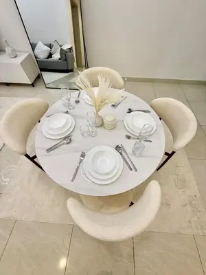 a white dining table with white plates and chairs at Premium 1BR, 2 Bath, Walk to Circle Mall, Pool & Gym in Dubai