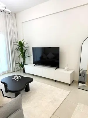a white living room with a large flat screen tv at Premium 1BR, 2 Bath, Walk to Circle Mall, Pool & Gym in Dubai