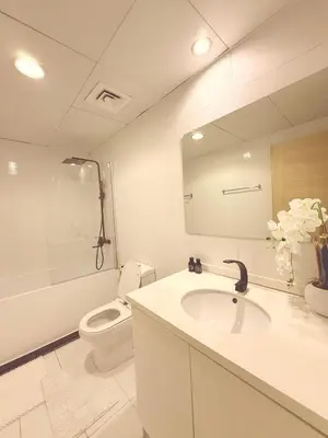 a bathroom with a sink and a toilet and a mirror at Premium 1BR, 2 Bath, Walk to Circle Mall, Pool & Gym in Dubai