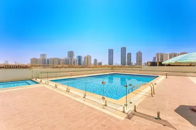 a large swimming pool with a city skyline in the background at Premium 1BR, 2 Bath, Walk to Circle Mall, Pool & Gym in Dubai
