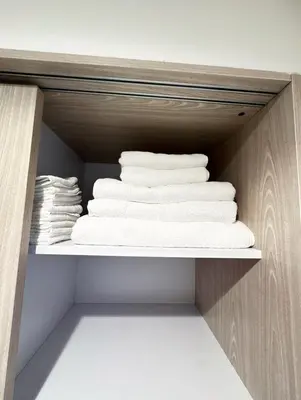 a closet with white towels on a shelf at Premium 1BR, 2 Bath, Walk to Circle Mall, Pool & Gym in Dubai