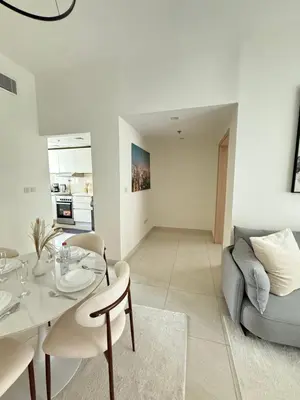 a white living room with a table and a couch at Premium 1BR, 2 Bath, Walk to Circle Mall, Pool & Gym in Dubai