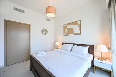 a white bedroom with a large bed and a door at BEST Burj Khalifa View 2br 3 beds in Dubai