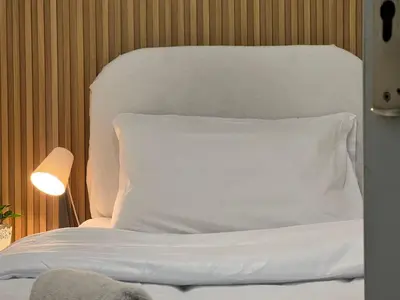 a white bed with a white pillow and a lamp at Minimalist Room In Al Barsha 1 Near Mall of Emirates in Dubai