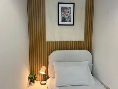 a bed with a white pillow and a picture on the wall at Elite Single Suite Room Partition In Tecom in Dubai
