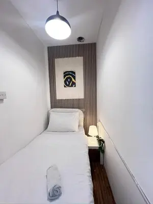 a small bedroom with a white bed and a lamp at Deluxe solo Room In Barsha Heights Tecom in Dubai