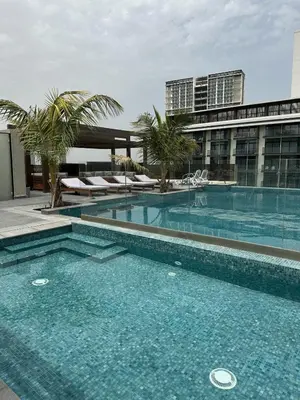 a large swimming pool with palm trees and a building at LUXE - Luxury Studio - Modern and Cozy in Dubai