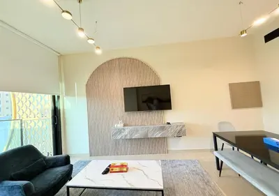 a living room with a couch and a tv on the wall at Binghatti Crescent Cozy 2 BR in Dubai