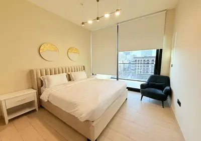 a bedroom with a bed and a chair and a window at Binghatti Crescent Cozy 2 BR in Dubai