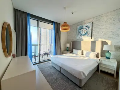 a bedroom with a large white bed and a balcony at Sunset Sea View at 5242 Emaar in Dubai