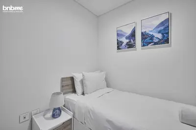 a white bedroom with a bed and two pictures on the wall at bnbmehomes - Downtown Views II in Dubai