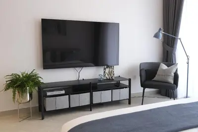 a living room with a tv and a chair at Beautiful Brand New Studio -Pool -Balcony -Parking in Dubai