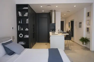 a bedroom with a bed and a desk and a kitchen at Beautiful Brand New Studio -Pool -Balcony -Parking in Dubai