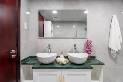 a bathroom with two sinks and a mirror at GuestReady - High Floor | Canal View Near Dubai Marina in Dubai