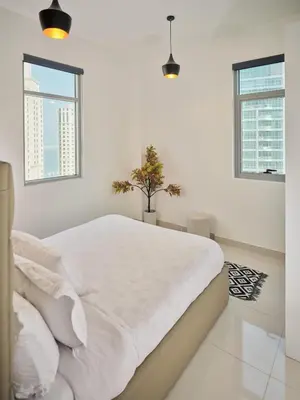 a white bedroom with a white bed and two windows at Best location in Marina & jbr and marina view 1 minute from JBR in Dubai