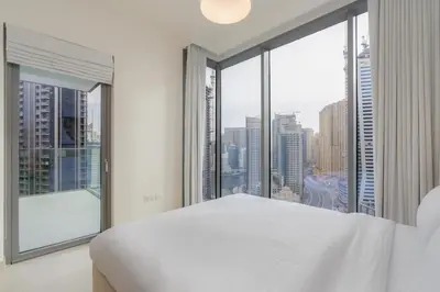 a bedroom with a white bed and a large window at Bespoke Holiday Homes - Luxury 2BR with Stunning Marina Views in LIV Marina in Dubai